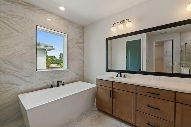 bathroom featuring independent shower and bath, vanity, and tile walls