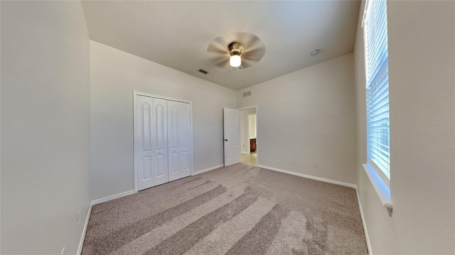 unfurnished bedroom with light carpet, a closet, and ceiling fan