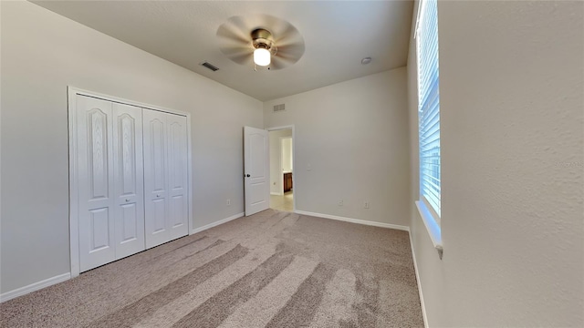 unfurnished bedroom featuring light colored carpet, ceiling fan, and a closet