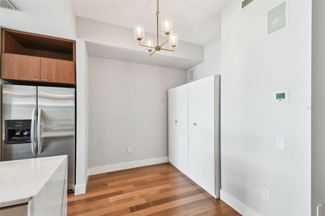 kitchen with hardwood / wood-style flooring, stainless steel fridge with ice dispenser, hanging light fixtures, and an inviting chandelier