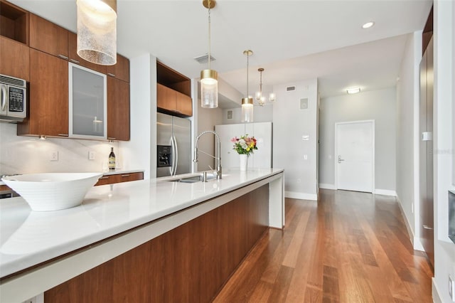 kitchen with dark wood-type flooring, hanging light fixtures, sink, appliances with stainless steel finishes, and a notable chandelier