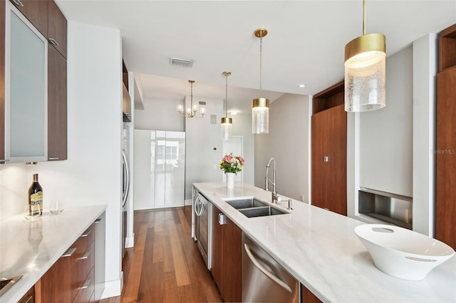 kitchen featuring dark hardwood / wood-style floors, sink, stainless steel dishwasher, and decorative light fixtures