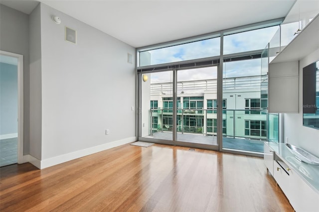 unfurnished room featuring light hardwood / wood-style floors and a wall of windows