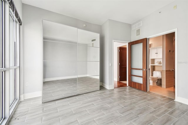 unfurnished bedroom featuring ensuite bath and a closet