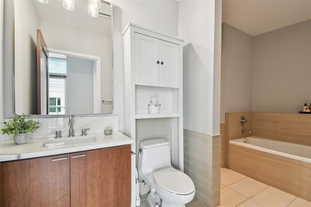 bathroom featuring tile patterned flooring, vanity, toilet, and tiled tub