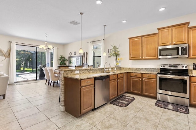 kitchen with kitchen peninsula, light stone counters, stainless steel appliances, and decorative light fixtures