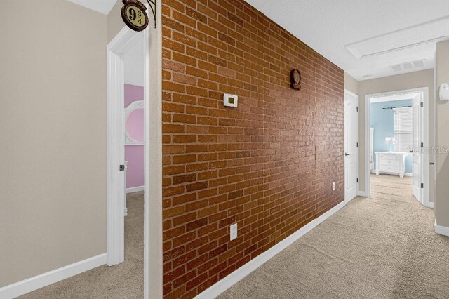 corridor featuring light carpet and brick wall