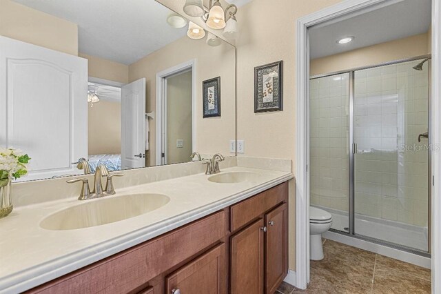 bathroom with vanity, a shower with door, ceiling fan, tile patterned flooring, and toilet