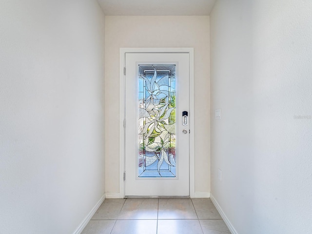 doorway with light tile patterned flooring and baseboards