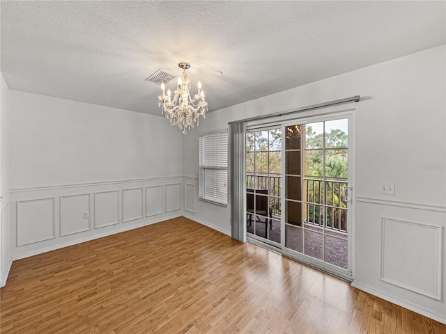 unfurnished dining area with wood-type flooring and an inviting chandelier