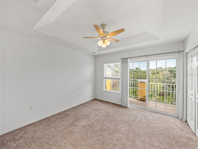 spare room with a tray ceiling, ceiling fan, and carpet floors