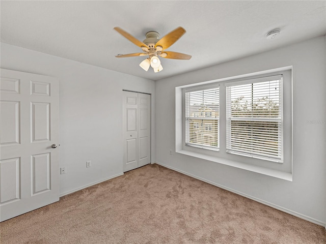 unfurnished bedroom with ceiling fan, light carpet, and a closet