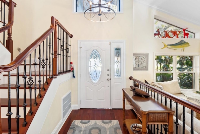 foyer entrance with a wealth of natural light, dark hardwood / wood-style flooring, and an inviting chandelier