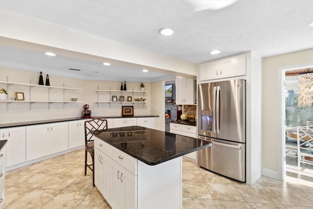 kitchen with white cabinets, a center island, stainless steel fridge, and a kitchen breakfast bar