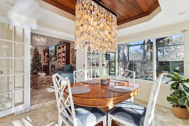 dining space with wood ceiling, crown molding, a tray ceiling, and an inviting chandelier