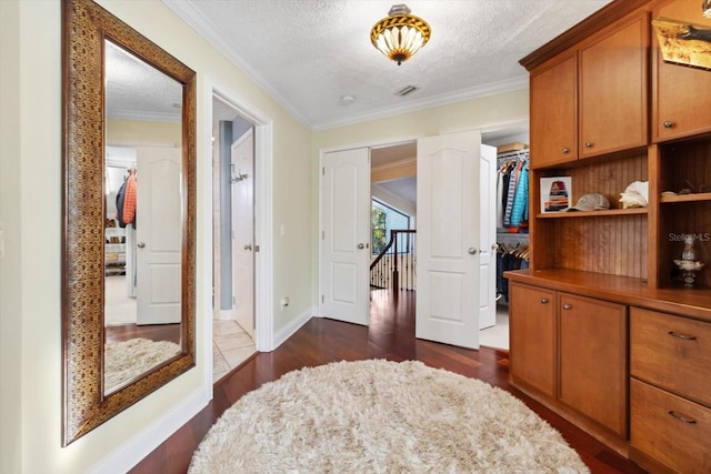 hall featuring dark wood-type flooring, a textured ceiling, and ornamental molding