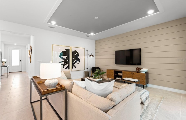 tiled living room featuring a raised ceiling and wood walls