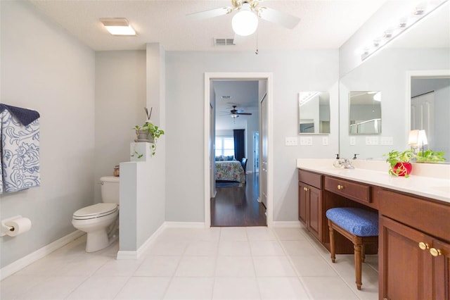 bathroom with tile patterned flooring, vanity, ceiling fan, toilet, and a textured ceiling