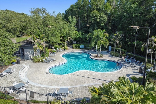 community pool with a patio area and fence