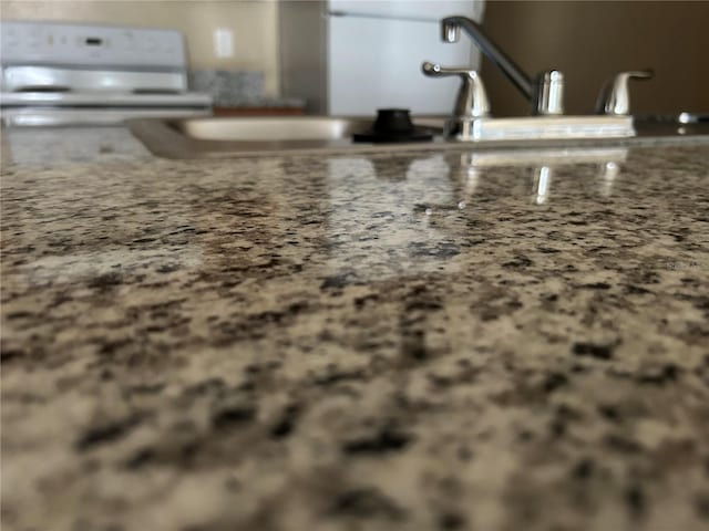 interior details featuring white range with electric stovetop, light stone countertops, and a sink