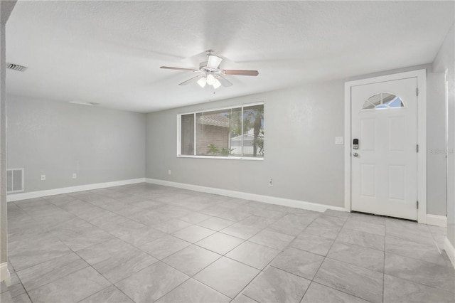 entryway featuring ceiling fan, light tile patterned flooring, and a textured ceiling