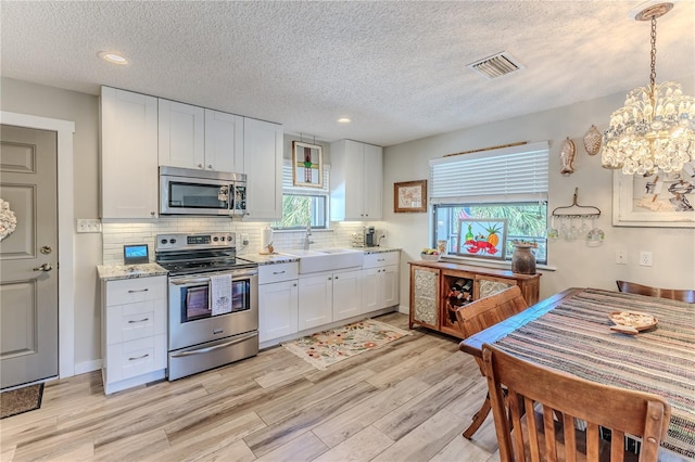 kitchen featuring white cabinets, a chandelier, stainless steel appliances, and a textured ceiling