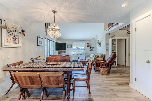 dining room featuring light hardwood / wood-style flooring, a textured ceiling, and an inviting chandelier