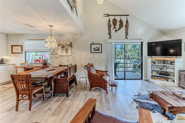 dining space with vaulted ceiling, light wood-type flooring, a textured ceiling, and a chandelier