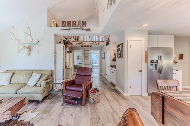 living room featuring a textured ceiling, light wood-type flooring, and a high ceiling