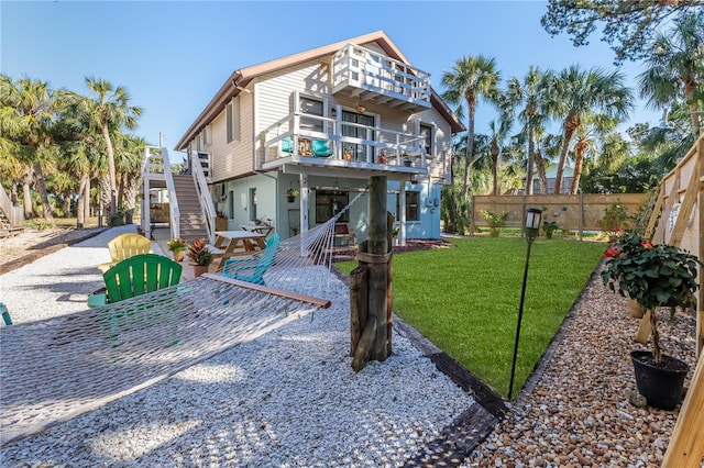 back of house with a balcony, a patio area, and a lawn