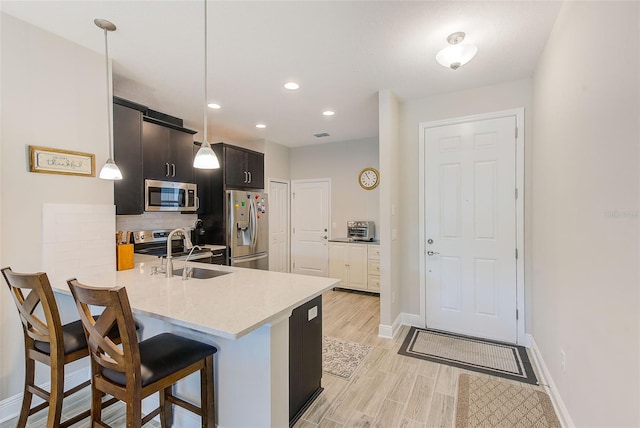 kitchen featuring appliances with stainless steel finishes, hanging light fixtures, a kitchen breakfast bar, sink, and kitchen peninsula