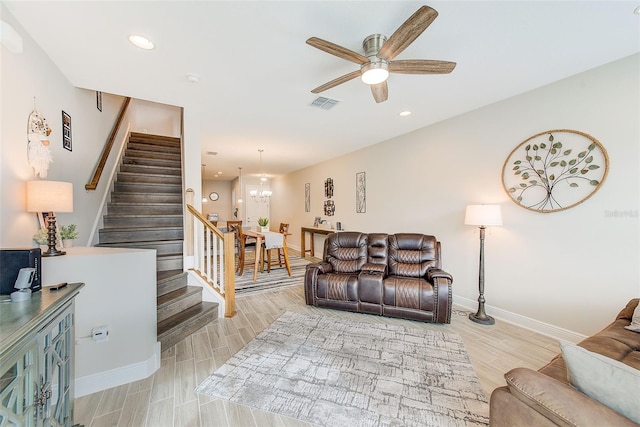 living room featuring ceiling fan with notable chandelier