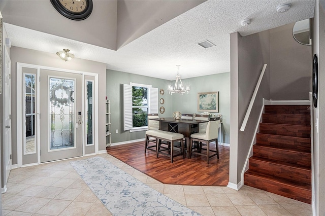 entrance foyer featuring light tile patterned flooring, a textured ceiling, and a notable chandelier