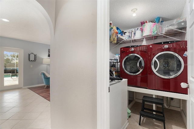 laundry room featuring washer and dryer, light tile patterned floors, and a textured ceiling