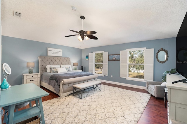 bedroom with ceiling fan, dark hardwood / wood-style flooring, and a textured ceiling