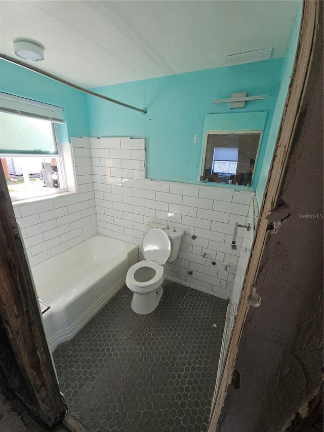 bathroom featuring tile patterned flooring, toilet, tile walls, and tiled shower / bath