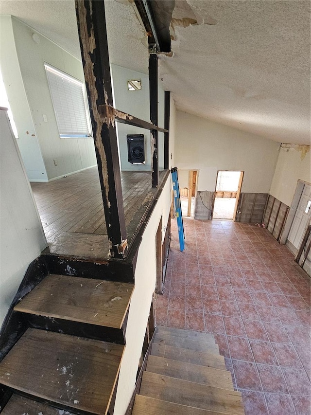 stairway featuring tile patterned flooring, a textured ceiling, and vaulted ceiling