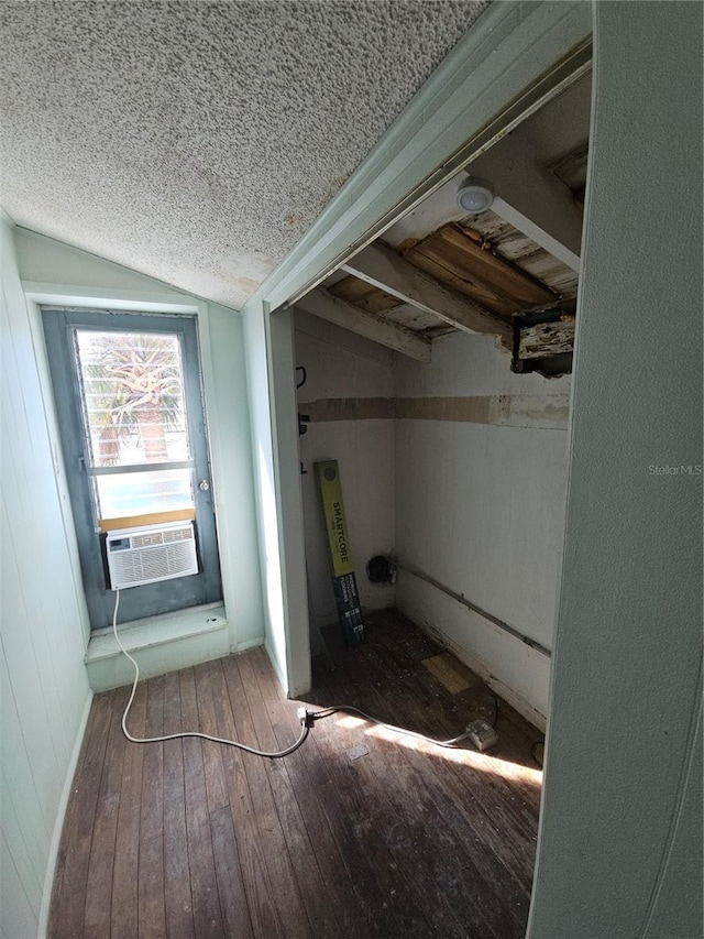 interior space featuring a textured ceiling, cooling unit, wood-type flooring, and lofted ceiling