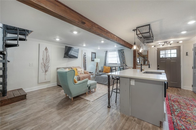 kitchen featuring pendant lighting, a center island with sink, beamed ceiling, sink, and a kitchen breakfast bar