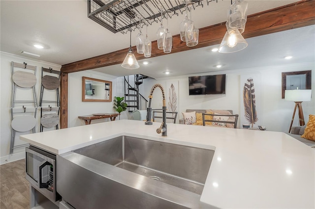 kitchen featuring hardwood / wood-style floors, decorative light fixtures, sink, stainless steel microwave, and crown molding