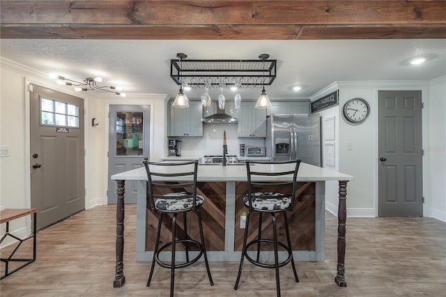 kitchen with wall chimney exhaust hood, stainless steel appliances, decorative backsplash, gray cabinets, and a breakfast bar