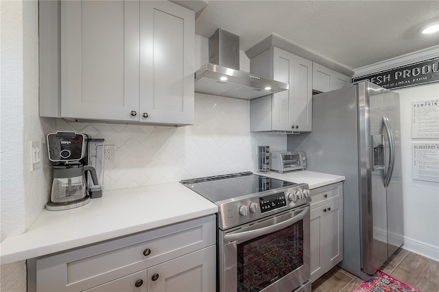 kitchen featuring backsplash, dark hardwood / wood-style floors, gray cabinets, appliances with stainless steel finishes, and wall chimney exhaust hood