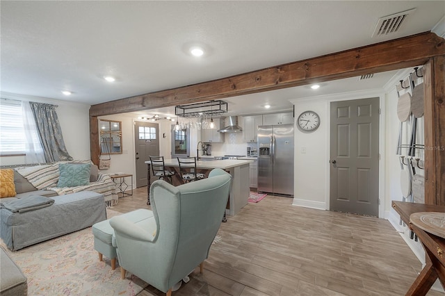 living room with sink, crown molding, a healthy amount of sunlight, and light wood-type flooring