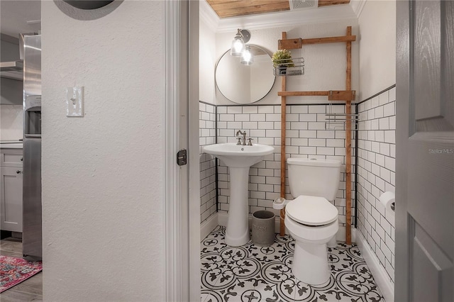 bathroom featuring toilet, tile walls, tile patterned floors, sink, and ornamental molding