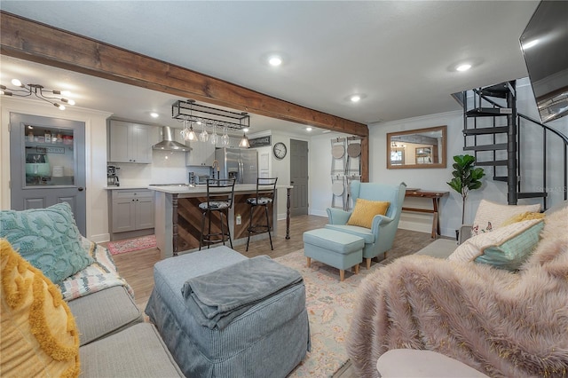 living room featuring beam ceiling, ornamental molding, and light hardwood / wood-style floors