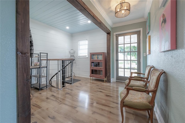 sitting room featuring light hardwood / wood-style floors, a wealth of natural light, crown molding, and a notable chandelier