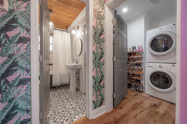 laundry area with wood ceiling, sink, ornamental molding, and stacked washer and dryer