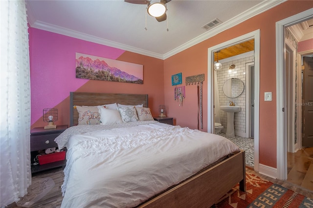 bedroom featuring hardwood / wood-style floors, ensuite bath, sink, ceiling fan, and crown molding