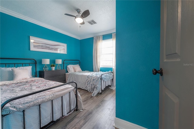 bedroom featuring ceiling fan, crown molding, a textured ceiling, and light hardwood / wood-style floors