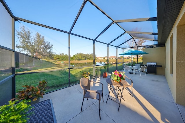 view of patio / terrace featuring glass enclosure, a grill, and a water view